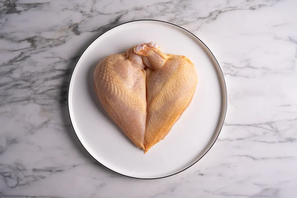 Rohes Hühnerfilet auf weißem Teller – Galeriebild 1/3 – Zotter Fleisch – Produkte